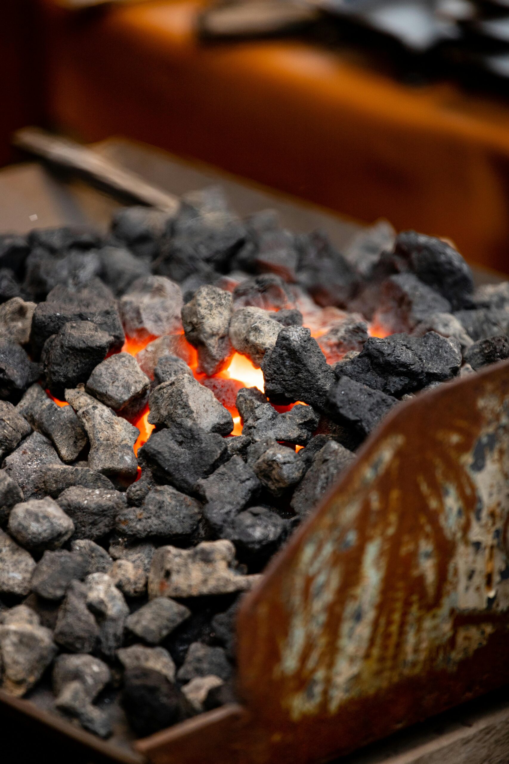 A detailed view of burning coals emitting heat and smoke in a fireplace.