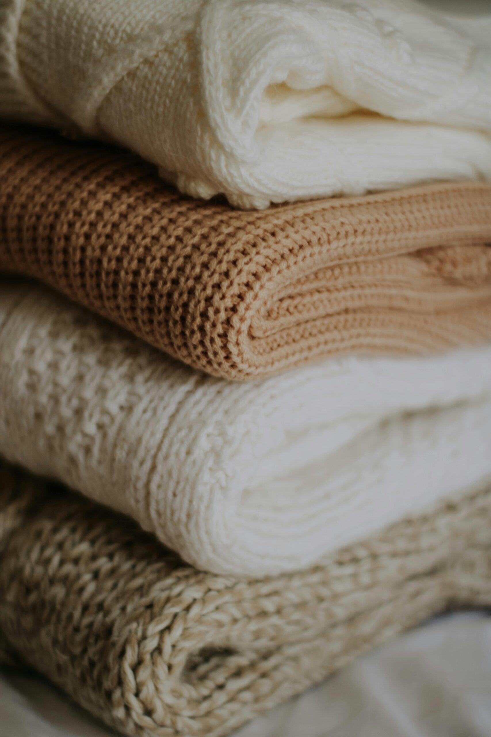 High-Grade Fabric & Textile Pile of beige and cream knitted blankets folded neatly for warmth and style.