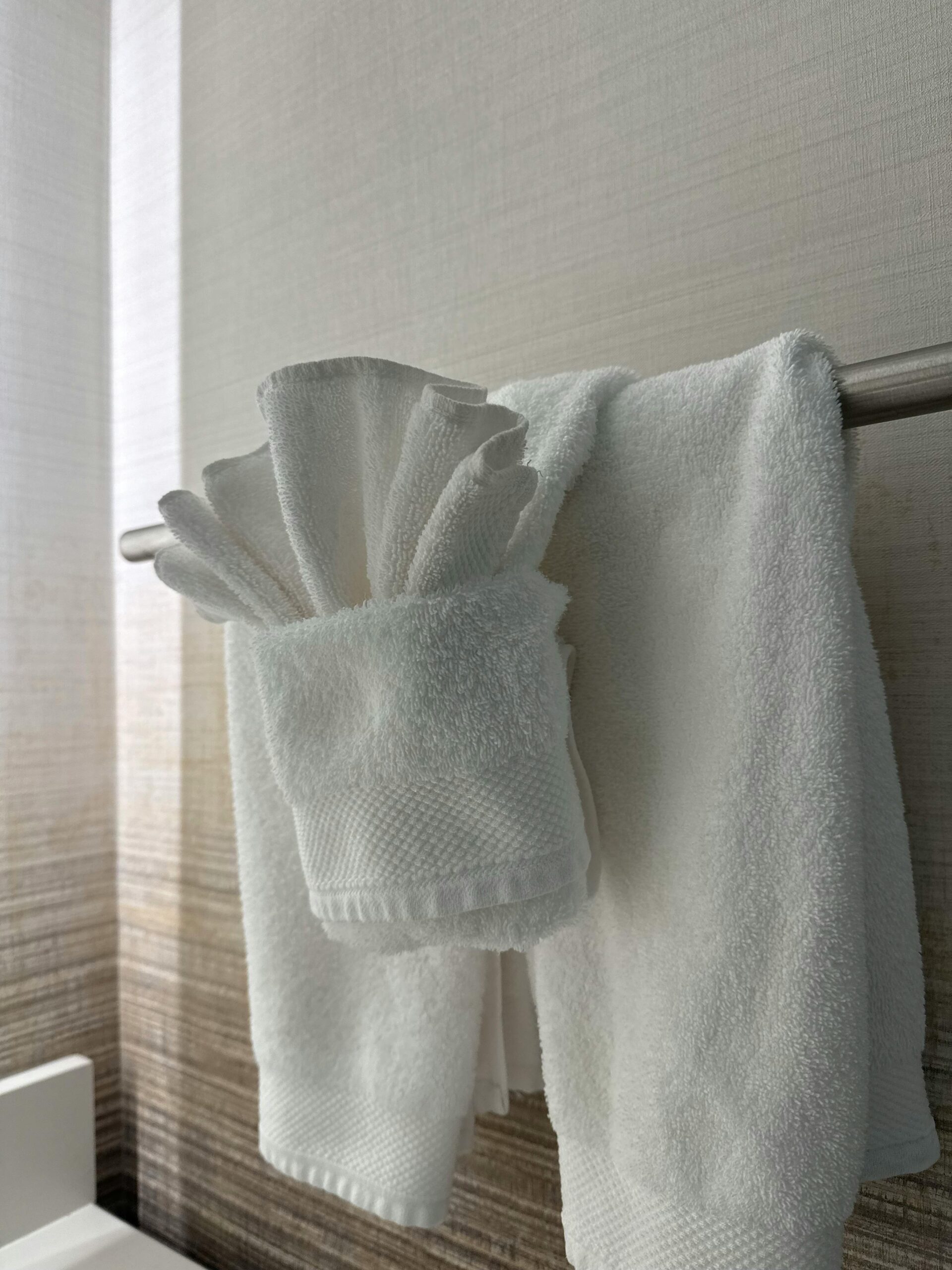 High-Absorbency Luxury Towels Stylish white towels artfully arranged in a luxurious modern bathroom space.