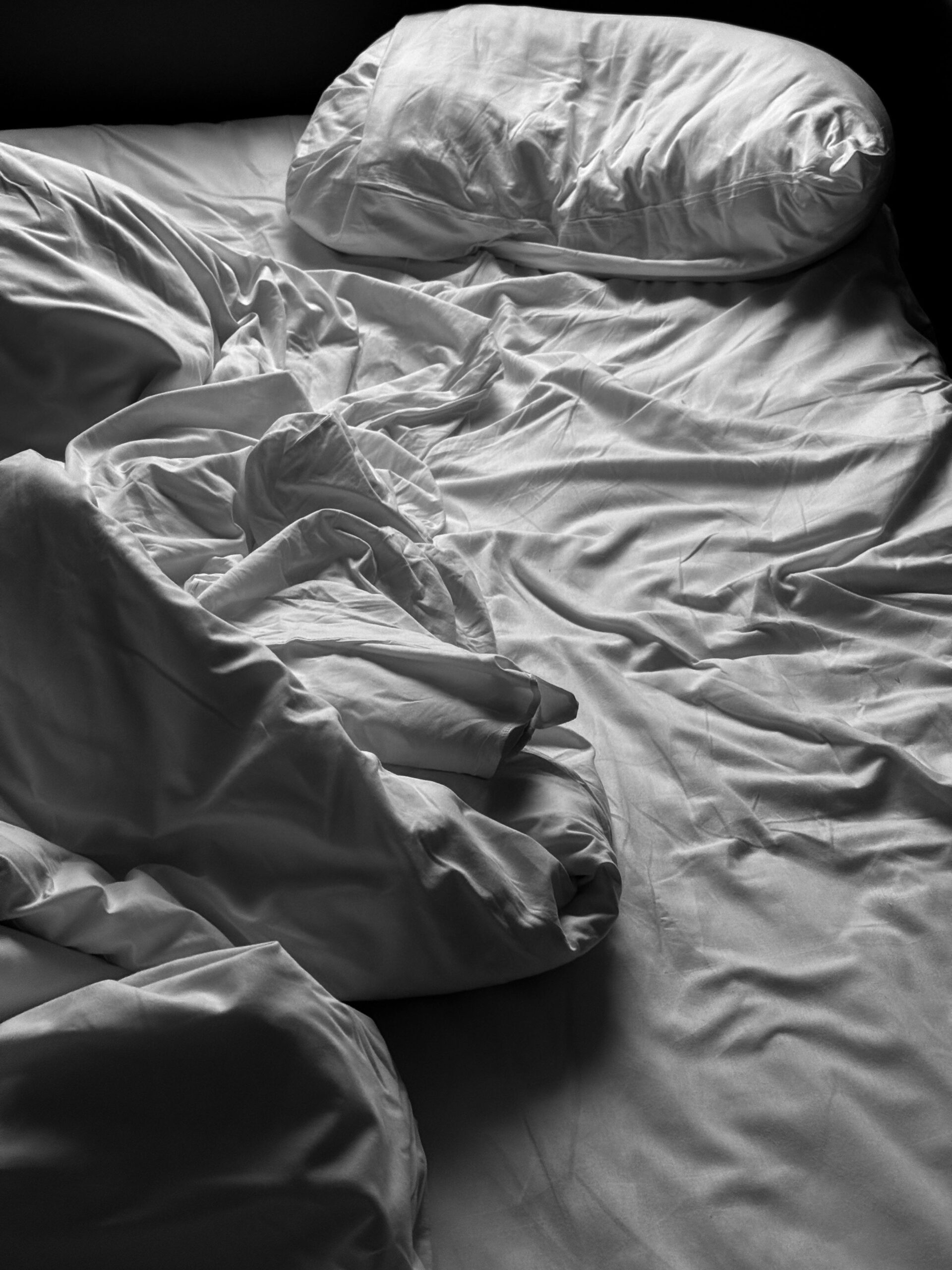 Artistic shot of messy bed linen conveying comfort and relaxation.