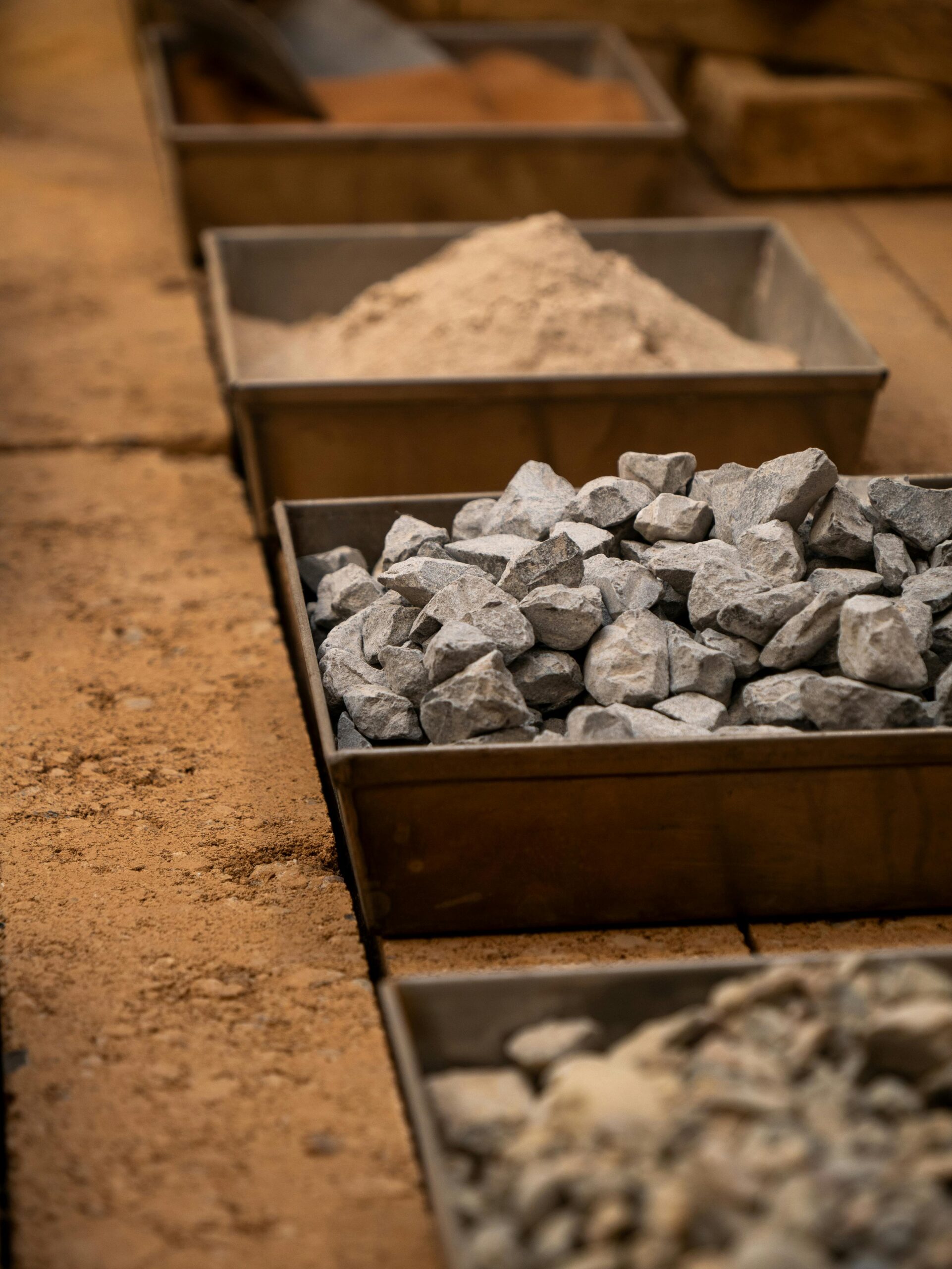 High-Purity Natural Gypsum Various construction materials including rocks, and sand in storage boxes.